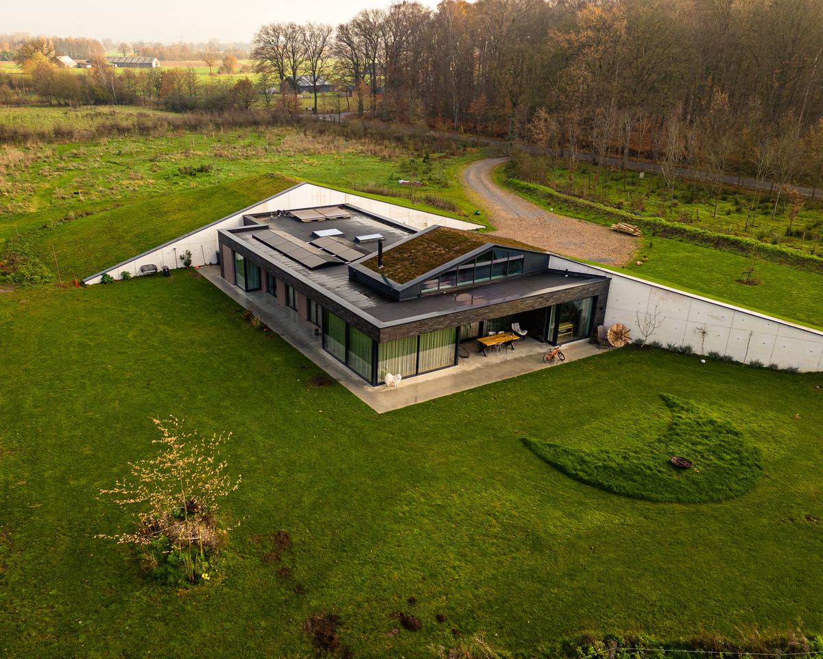 Woning met groen sedumdak en zonnepanelen, opgenomen in het landschap