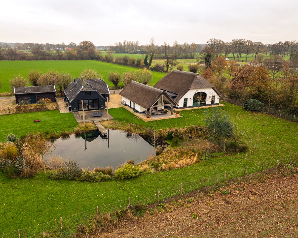 Witte boerderij met vijver in het landschap, gerenoveerd door Groters